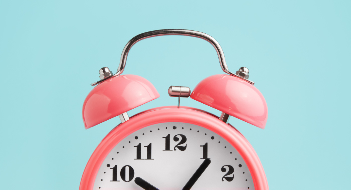 pink alarm clock on a blue background