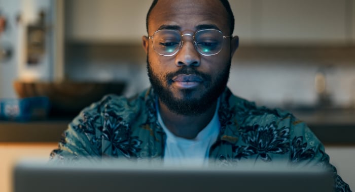 Man sitting, looking at a laptop