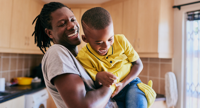 Person holding up child while they both laugh