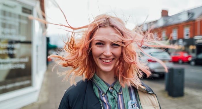 person smiling into the camera with hair blowing around their face