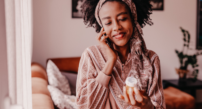 person looking at a prescription bottle while on the phone