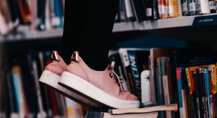 person standing on their tippy toes in a library