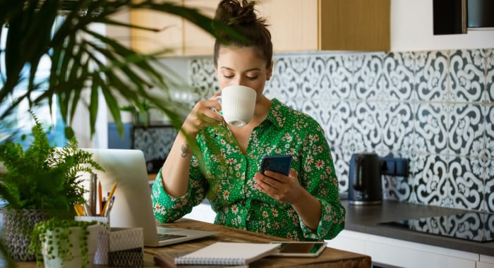 Woman sipping coffee and looking at her phone