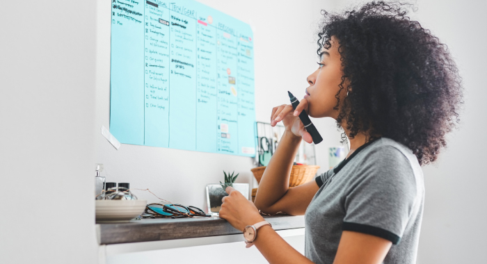 Woman looking at a homemade spreadsheet taped to her wall