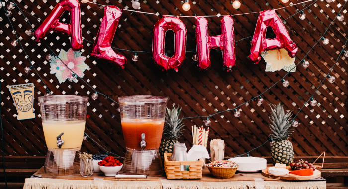 Aloha balloon sign hanging over a table with pitchers of drinks.