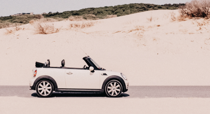 A tan mini cooper driving along the sand