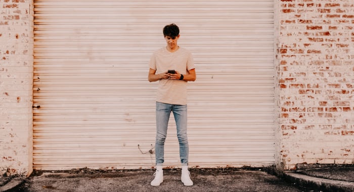 person standing in front of a closed garage door and looking down at their phone