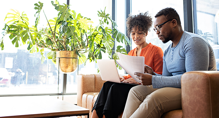 two people sitting on the couch going over paperwork