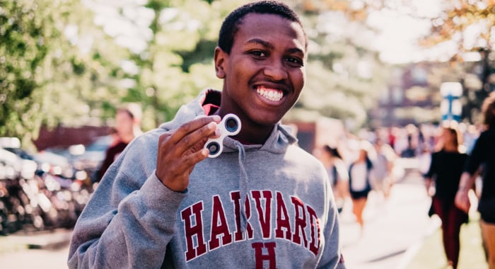 Person smiling at the camera and wearing a Harvard sweatshirt 