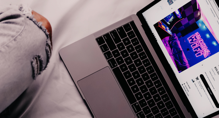 person sitting on a bed with a laptop open