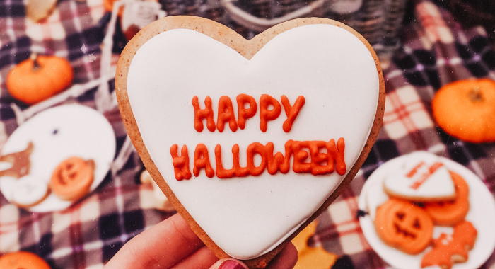 heart-shaped cookie with "Happy Halloween" written in orange icing