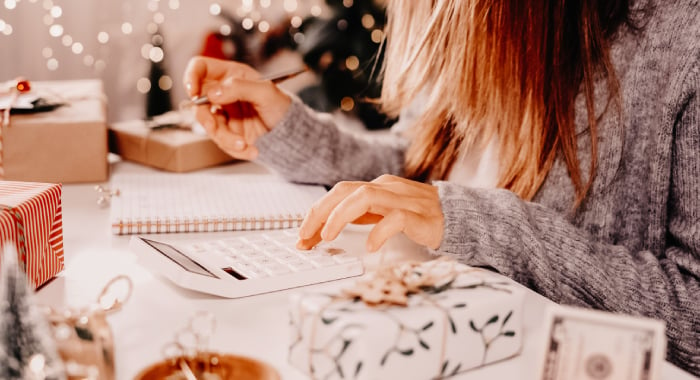 person looking at a calculator, surrounded by holiday decor