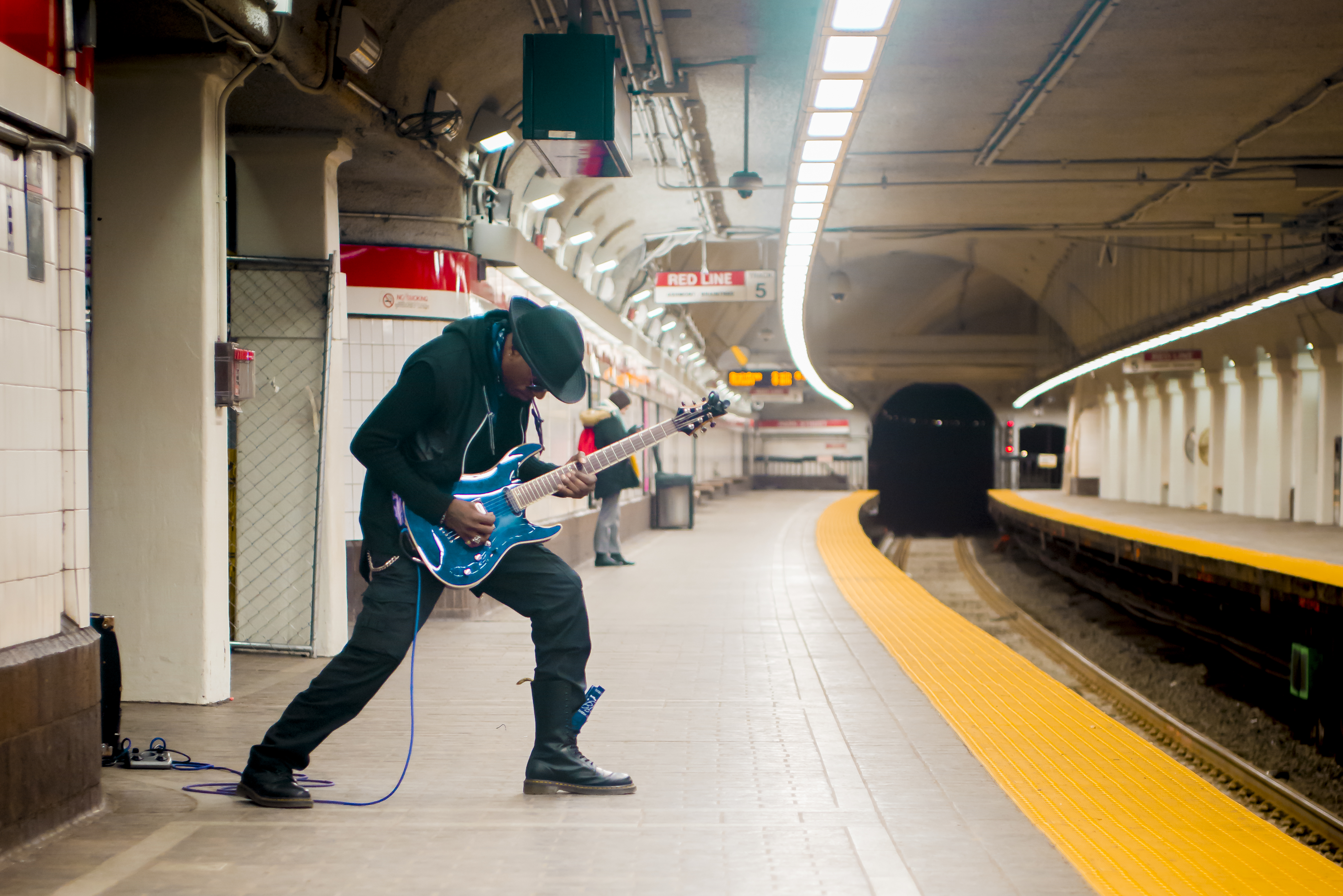 Man playing the guitar at a T stop