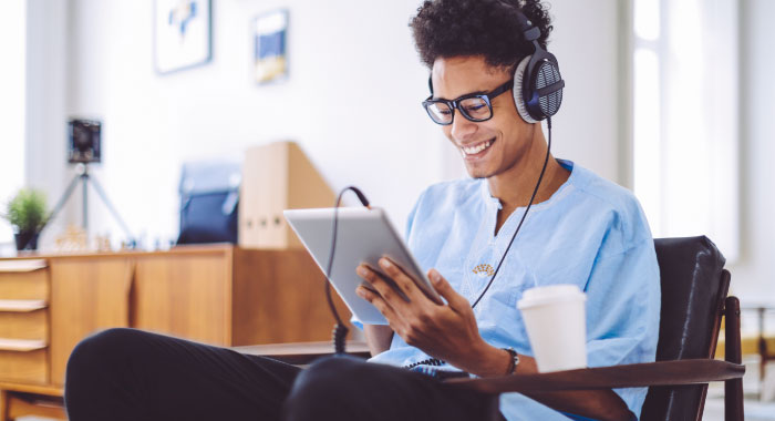 Young man looking at something on a tablet while wearing headphones.