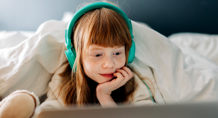 Young girl with headphones on watching something on the computer